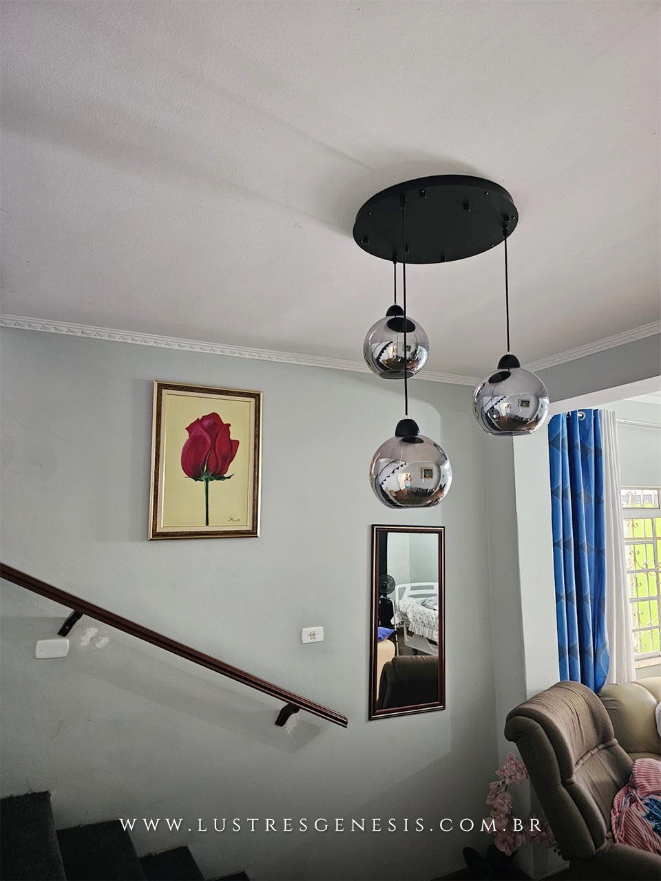 Lustre pendente Sarvah com 3 globos de vidro, instalado em sala de estar próxima à escada, destacando design moderno e sofisticado.